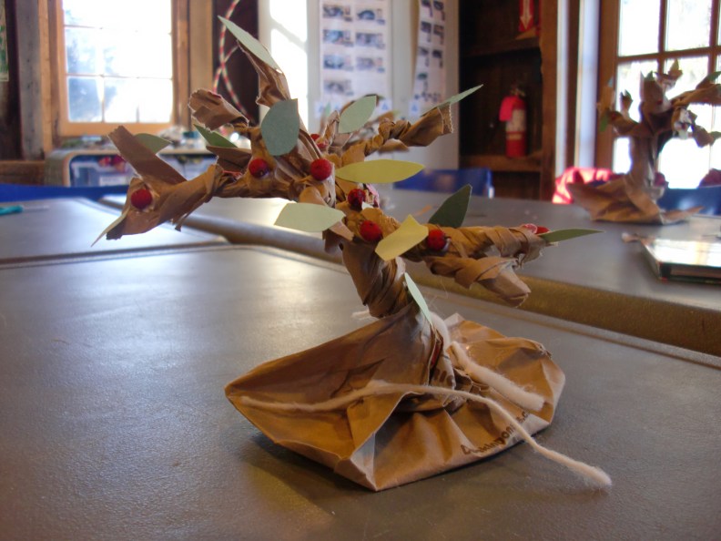 My son's finished tree, with paper leaves and flowers, dried winterberries for the apples, and spun wool for the roots.